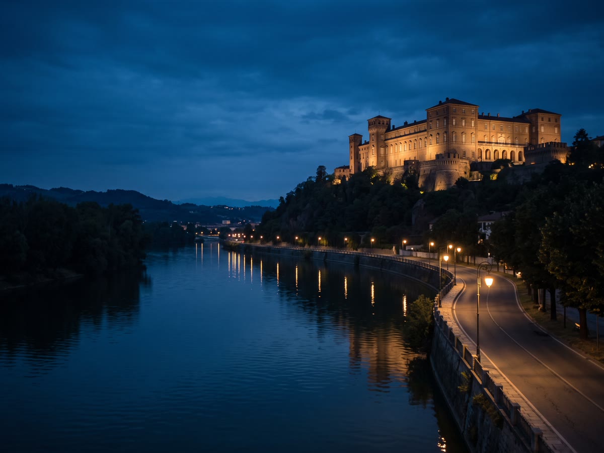 Castello di Moncalieri sulla collina all'ora blu con il Po e una strada lungofiume illuminata