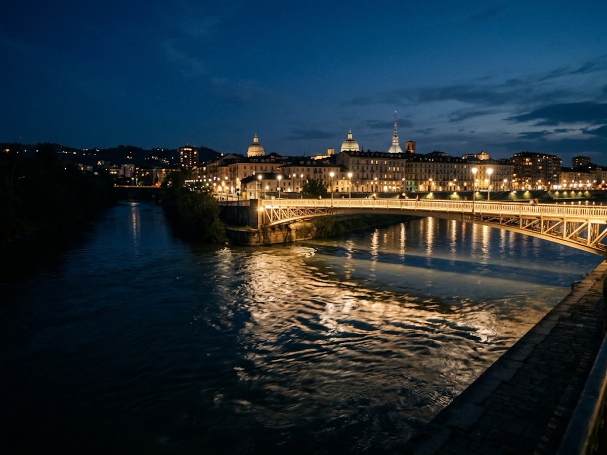 Confluenza della Dora nel Po all'ora blu con una passerella illuminata e riflessi della città