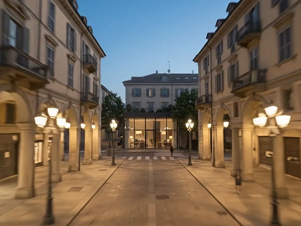 Una via con i portici a Torino all'ora blu e, in fondo, la vetrata illuminata dello studio